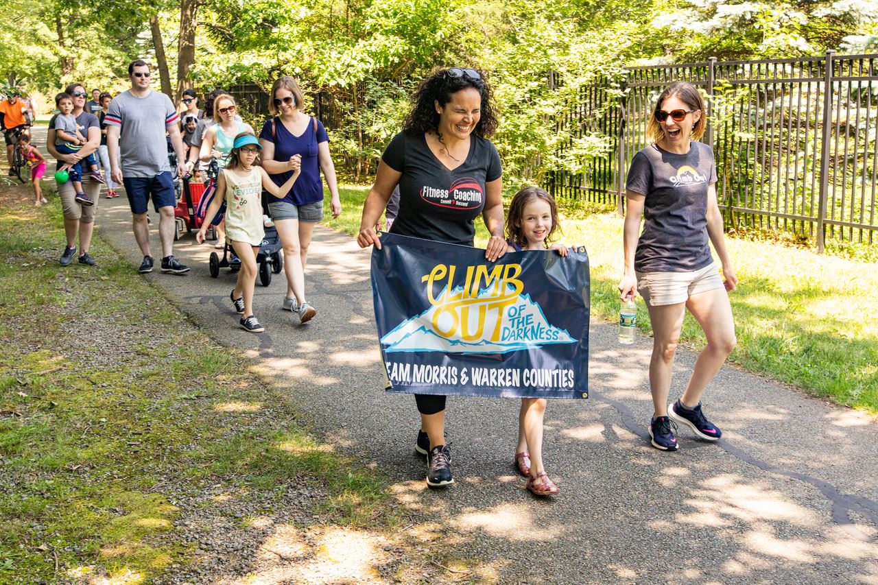 Laura, Her Daughter Avery and Others Walking with the "Climb Out of the Darkness" Banner